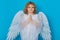 Angel prayer. Valentine& x27;s day. Blonde cute child with angel wings on a blue isolated studio background. Happy angel