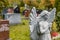 Angel statue praying in front of several tombstones on a graveyard in Fall