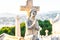 Angel statue with wings against tombstone cross in old cemetery. stone saint angel with praying hands at cemetery. Graveyard ancie