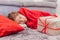 Angelic daughter is sleeping on the carpet, covered with red blanket, with Christmas gift on her side.