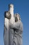 Angelic figure stands against a serene sky as they hold a cross in their hands