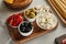 Angle view of boards with breadsticks, garlic and bowls with olives, mozzarella and marinated chili peppers on white