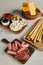 Angle view of boards with breadsticks, salami slices, cheese and antipasto ingredients on white