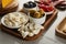 Angle view of boards with garlic and bowls with olives, mozzarella and marinated chili peppers on white