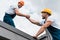 Angle view of cheerful handymen in helmets holding hands