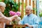 Angle view of cheerful senior woman holding teapot near cup and happy husband