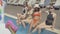 Angle view of four happy Caucasian adult women sitting at poolside and splashing water with legs. Portrait of relaxed