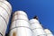 Angle view looking up at three agricultural feed grain and corn silo buildings against a blue sky in rural heartland america