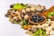 Angled close-up shot of black herbal tablets in a wooden spoon with scattered herbs and spices on a white background