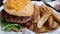 Angled down view of a greasy cheeseburger and crispy steak fries, served in a basket at a local burger dive