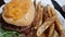 Angled down view of a greasy cheeseburger and crispy steak fries, served in a basket at a local burger dive