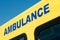 Angled view of AMBULANCE sign on yellow emergency vehicle.