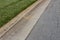 Angled view formed concrete curb, green grass and asphalt street