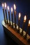 Angled view of a lighted Hanukkah menorah against a blue background