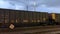 Angled view of a moving freight train carrying cargo passes through train station crossing at Ardmore Ave. in Villa Park, IL