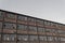 Angled view of old brick warehouse with walls of broken out windows, gray sky copy space