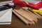 Angled view over a wooden desk with school supplies on it. Stepler, colored pencils, notebooks, calculator, scissors, tapes, paint