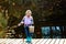 An angler girl with a fishing rod and a bucket with a catch stands on the bridge