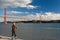 Angler at Lisbon\'s riverfront. The 25 de Abril Bridge spans the river Tagus and reaches beyond the statue of Cristo Rei.