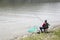 Angler Sitting On The River Coast And Patiently Waiting For Fish To Take A Bait