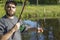 Angler stands over the water and shows a set for catching live fish.