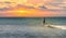 An angler in waterproof trousers is fishing in the Baltic Sea. He is standing on a stone in the water