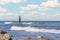 An angler in waterproof trousers is fishing in the Baltic Sea. He is standing on a stone in the water