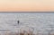 An angler in waterproof trousers is fishing in the Baltic Sea. He is standing on a stone in the water