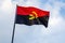 Angola flag waving in front of a blue sky