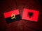 Angolan flag with Albanian flag on a tree stump isolated