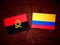 Angolan flag with Colombian flag on a tree stump isolated