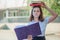 Angrily pursed girl holds two books on her head red and green and smiles. Schoolgirl on the background of the school after the