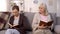 Angry aged lady looking senior woman reading book sofa, communication conflict