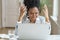 Angry annoyed afro businesswoman screaming, wear headphones talking to a bad customer work on laptop