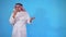 Angry Arab man impulsively talking on the phone standing on a blue background