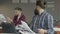 Angry bearded man sitting in the foreground studying papers in the office. Worker turns back to his colleague and throw