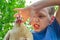 The angry boy holds a white chicken in his hands and grabs her by the neck