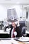 Angry businessman hold rubbish bin on his head at office