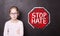 Angry child girl at the chalkboard with `STOP HATE` sign