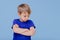 Angry child llittle boy dressed in blue T-shirt,  on blue background