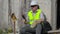 Angry construction worker with tablet PC near wall