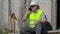 Angry construction worker talking on smart phone near wall