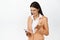 Angry corporate woman shouting at her mobile phone, staring at smartphone with annoyed face expression, white background