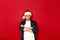 angry disgruntled man folded his arms with cross on chest and offended in Santa Claus Christmas hat. isolated on red