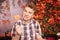 Angry disgruntled teenager in plaid shirt sits with pumpkin Lollipop and shows an evil face against the background of