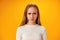 Angry dissatisfied teen girl against yellow background