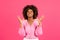 Angry excited upset young black curly female with braces in casual raising her hands and looking up