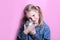 Angry funny young girl with silver piggy bank on pink background. save money concept.