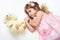 Angry girl child with teddy bear lie on white towel in bed, dressed in pink