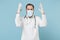Angry irritated male doctor man in medical gown sterile face mask gloves isolated on blue background. Epidemic pandemic